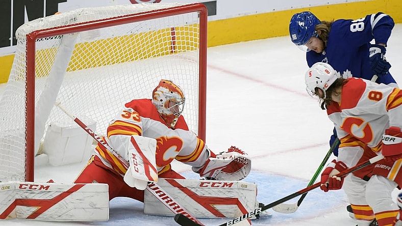 Feb 22, 2021; Toronto, Ontario, CAN;   Calgary Flames goalie David Rittich (33) makes a save as defenseman Christopher Tanev (8) battles with Toronto Maple Leafs forward William Nylander (88) in the first period at Scotiabank Arena. Mandatory Credit: Dan Hamilton-USA TODAY Sports