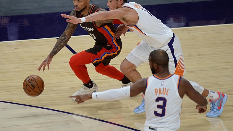 Feb 22, 2021; Phoenix, Arizona, USA; Portland Trail Blazers guard Damian Lillard (0) dribbles against Phoenix Suns guard Devin Booker (1) during the first half at Phoenix Suns Arena. Mandatory Credit: Joe Camporeale-USA TODAY Sports