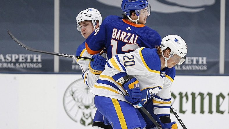 Feb 22, 2021; Uniondale, New York, USA; New York Islanders center Mathew Barzal (13) is checked by Buffalo Sabres defenseman Henri Jokiharju (10) and center Cody Eakin (20) during the second period at Nassau Veterans Memorial Coliseum. Mandatory Credit: Andy Marlin-USA TODAY Sports