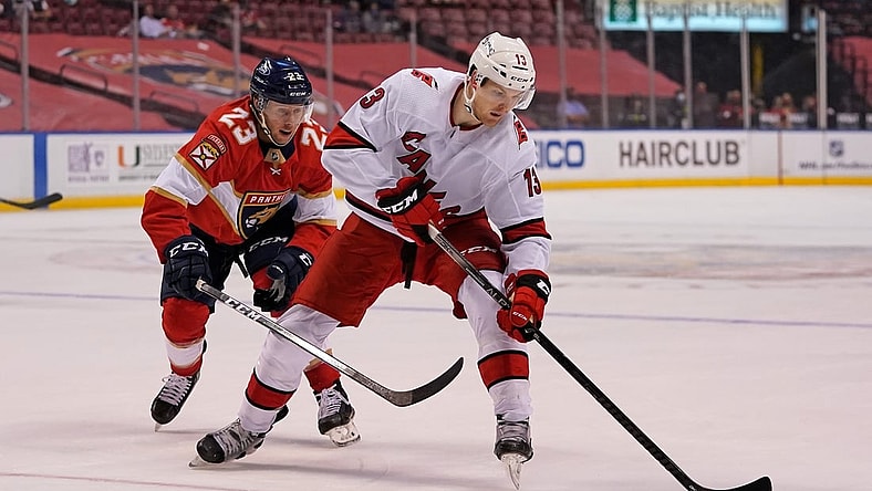 Mar 1, 2021; Sunrise, Florida, USA; Florida Panthers center Carter Verhaeghe (23) reaches for the puck on Carolina Hurricanes left wing Warren Foegele (13) during the first period at BB&T Center. Mandatory Credit: Jasen Vinlove-USA TODAY Sports