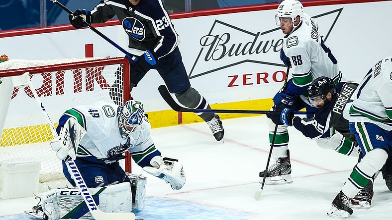 Mar 2, 2021; Winnipeg, Manitoba, CAN;  Vancouver Canucks goalie Braden Holtby (49) smothers the puck in front of Winnipeg Jets forward Matthieu Perreault (85) during the first period at Bell MTS Place. Mandatory Credit: Terrence Lee-USA TODAY Sports