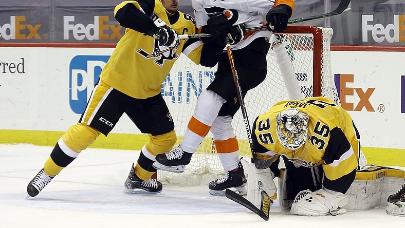 Mar 4, 2021; Pittsburgh, Pennsylvania, USA;  Pittsburgh Penguins center Sidney Crosby (87) defends Philadelphia Flyers left wing Scott Laughton (21) as Pittsburgh Penguins goaltender Tristan Jarry (35) covers the puck after a save during the second period at PPG Paints Arena. Mandatory Credit: Charles LeClaire-USA TODAY Sports