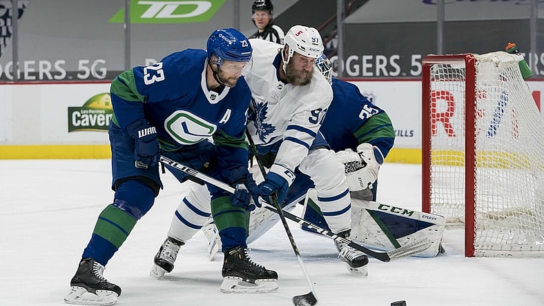 Mar 6, 2021; Vancouver, British Columbia, CAN; Vancouver Canucks defenseman Alexander Edler (23) checks Toronto Maple Leafs forward  Joe Thornton (97) in the first period at Rogers Arena. Mandatory Credit: Bob Frid-USA TODAY Sports