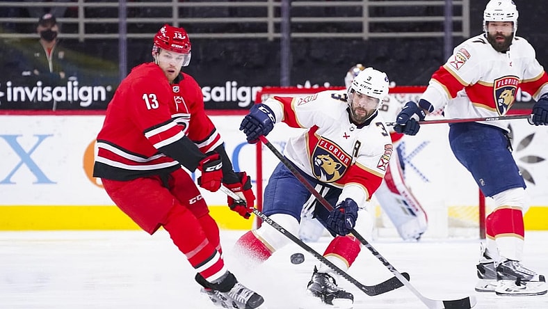 Mar 7, 2021; Raleigh, North Carolina, USA;  Florida Panthers defenseman Keith Yandle (3) chips the puck away from Carolina Hurricanes left wing Warren Foegele (13) during the first period at PNC Arena. Mandatory Credit: James Guillory-USA TODAY Sports