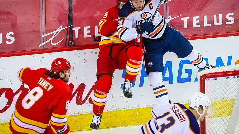 Mar 15, 2021; Calgary, Alberta, CAN; Edmonton Oilers center Connor McDavid (97) checks into the boards Calgary Flames defenseman Noah Hanifin (55) during the second period at Scotiabank Saddledome. Mandatory Credit: Sergei Belski-USA TODAY Sports