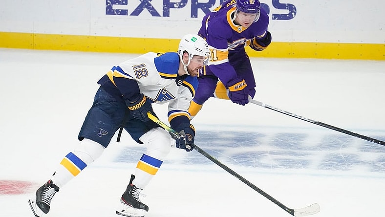 Mar 17, 2021; Los Angeles, California, USA; St. Louis Blues left wing Zach Sanford (12) moves the puck down the ice as Los Angeles Kings left wing Carl Grundstrom (91) gives chase during the first period at Staples Center. Mandatory Credit: Robert Hanashiro-USA TODAY Sports