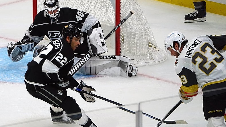 Mar 21, 2021; Los Angeles, California, USA; Vegas Golden Knights defenseman Alec Martinez (23) moves in for a shot as Los Angeles Kings left wing Andreas Athanasiou (22) helps goaltender Calvin Petersen (40) defend the goal during the first period at Staples Center. Mandatory Credit: Gary A. Vasquez-USA TODAY Sports