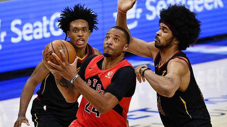 Mar 21, 2021; Cleveland, Ohio, USA; Toronto Raptors forward Norman Powell (24) drives to the basket between Cleveland Cavaliers guard Collin Sexton (2) and center Jarrett Allen (31) during the third quarter at Rocket Mortgage FieldHouse. Mandatory Credit: Ken Blaze-USA TODAY Sports