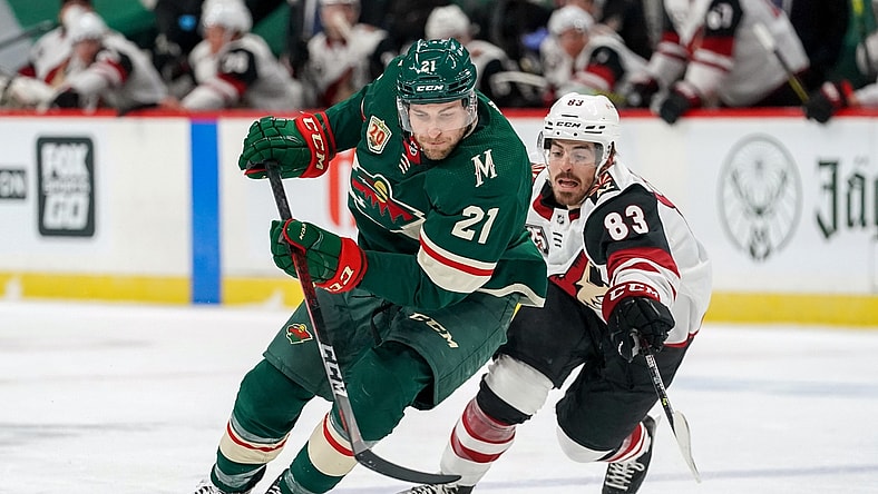 Mar 14, 2021; Saint Paul, Minnesota, USA;  Minnesota Wild defenseman Carson Soucy (21) protects the puck from Arizona Coyotes right wing Conor Garland (83) at Xcel Energy Center. Mandatory Credit: Nick Wosika-USA TODAY Sports