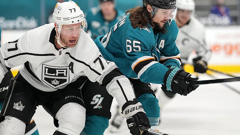 Mar 22, 2021; San Jose, California, USA;  Los Angeles Kings center Jeff Carter (77) and San Jose Sharks defenseman Erik Karlsson (65) chase after the puck during the first period at SAP Center at San Jose. Mandatory Credit: Stan Szeto-USA TODAY Sports