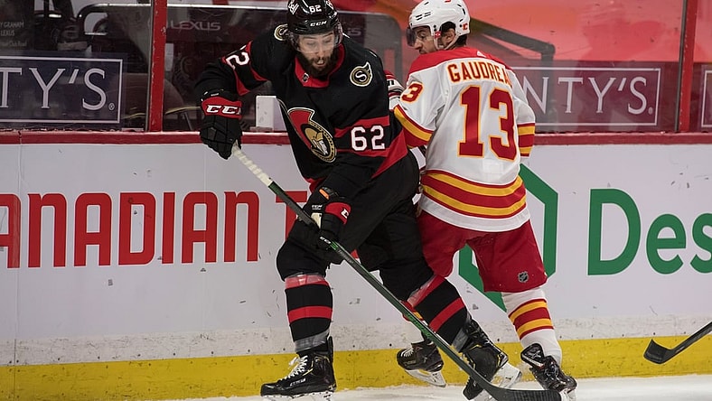 Mar 24, 2021; Ottawa, Ontario, CAN; Ottawa Senators center Clark Bishop (62) steals the puck from Calgary Flames left wing Johnny Gaudreau (13) during the first period at the Canadian Tire Centre. Mandatory Credit: Marc DesRosiers-USA TODAY Sports