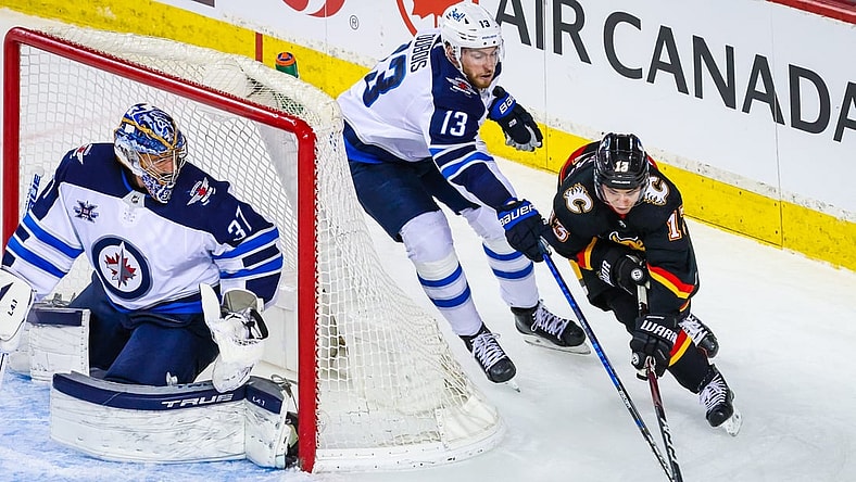Mar 26, 2021; Calgary, Alberta, CAN; Winnipeg Jets goaltender Connor Hellebuyck (37) guards his net as Calgary Flames left wing Johnny Gaudreau (13) and Winnipeg Jets center Pierre-Luc Dubois (13) battle for the puck during the second period at Scotiabank Saddledome. Mandatory Credit: Sergei Belski-USA TODAY Sports