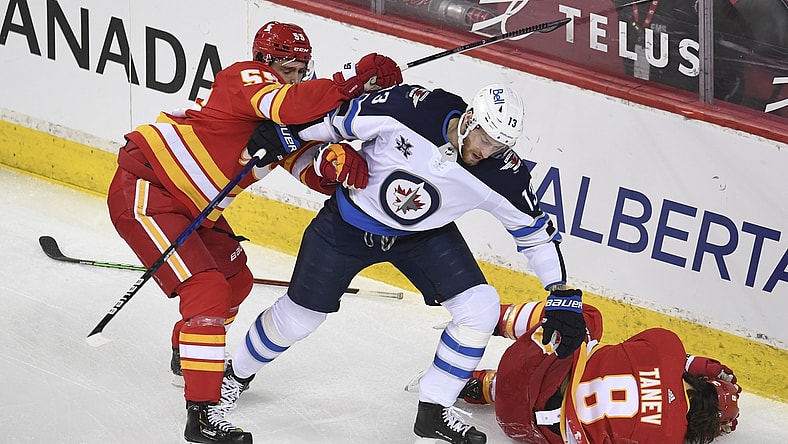 Mar 29, 2021; Calgary, Alberta, CAN; Calgary Flames defenseman Noah Hanifin (55) reacts to a hit on defenseman Christopher Tanev (8) from Winnipeg Jets forward Pierre-Luc Dubois (13) during the first period at Scotiabank Saddledome. Mandatory Credit: Candice Ward-USA TODAY Sports