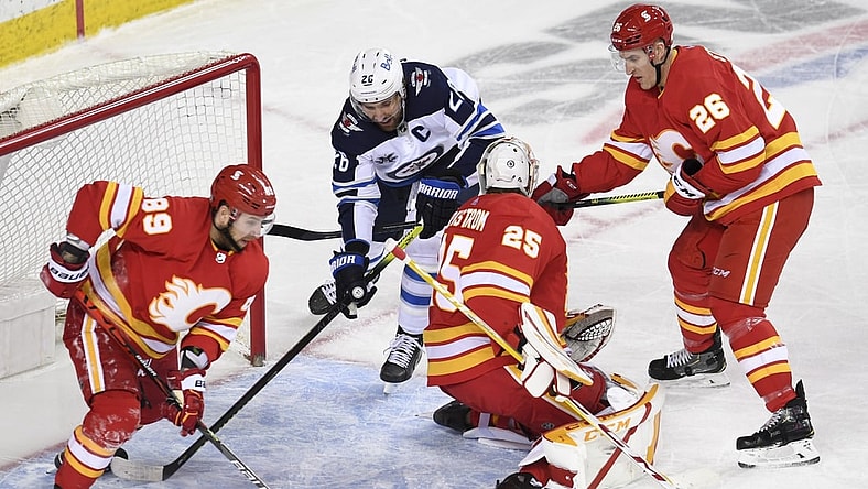 Mar 29, 2021; Calgary, Alberta, CAN; Winnipeg Jets forward Blake Wheeler (26) battles for the puck with Calgary Flames defenseman Nikita Nesterov (89) goalie Jacob Markstrom (25) and defenseman Michael Stone (26) during the second period at Scotiabank Saddledome. Mandatory Credit: Candice Ward-USA TODAY Sports
