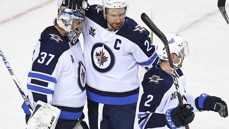 Mar 29, 2021; Calgary, Alberta, CAN; Winnipeg Jets goalie Connor Hellebuyck (37) celebrates with forward Blake Wheeler (26) after a victory over the Calgary Flames at Scotiabank Saddledome. Mandatory Credit: Candice Ward-USA TODAY Sports