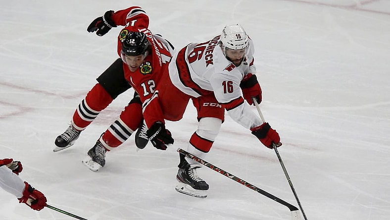 Mar 30, 2021; Chicago, Illinois, USA; Chicago Blackhawks Alex DeBrincat (12) battles for the puck with Carolina Hurricanes Vincent Trocheck (16) during the third period at United Center. Mandatory Credit: Eileen T. Meslar-USA TODAY Sports