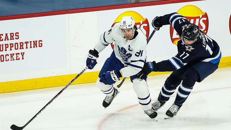 Mar 31, 2021; Winnipeg, Manitoba, CAN; Toronto Maple Leafs forward John Taveres (91) skates with the puck while defended by Winnipeg Jets forward Adam Lowry (17) during the first period at Bell MTS Place. Mandatory Credit: Terrence Lee-USA TODAY Sports