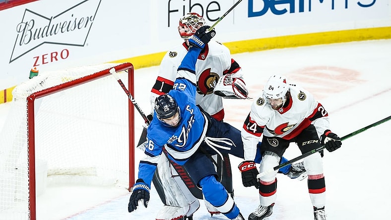 Feb 13, 2021; Winnipeg, Manitoba, CAN;  Ottawa Senators defenseman Christian Wolanin (24) hits Winnipeg Jets forward Blake Wheeler (26) in front of Ottawa Senators goalie Marcus Hogberg (1) during the third period at Bell MTS Place. Mandatory Credit: Terrence Lee-USA TODAY Sports