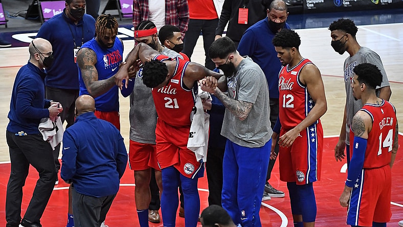 Mar 12, 2021; Washington, District of Columbia, USA; Philadelphia 76ers center Joel Embiid (21) is helped to his feet by teammates after suffering an apparent leg injury against the Washington Wizards during the third quarter at Capital One Arena. Mandatory Credit: Brad Mills-USA TODAY Sports