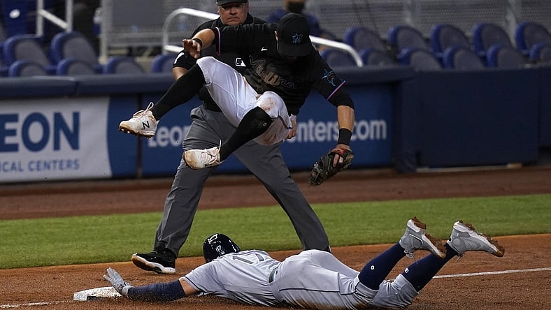 Apr 3, 2021; Miami, Florida, USA; Miami Marlins third baseman Jon Berti (5) leaps over Tampa Bay Rays right fielder Austin Meadows (17) as he steals third base safely in the 3rd inning at loanDepot park. Mandatory Credit: Jasen Vinlove-USA TODAY Sports