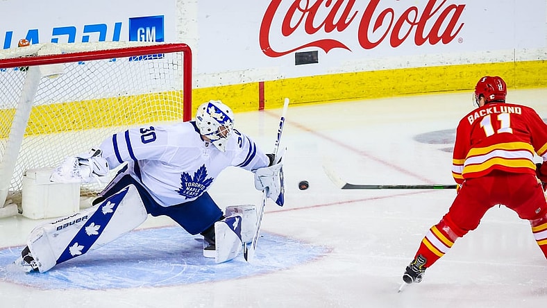 Apr 4, 2021; Calgary, Alberta, CAN; Toronto Maple Leafs goaltender Michael Hutchinson (30) makes a save against Calgary Flames center Mikael Backlund (11) during the first period at Scotiabank Saddledome. Mandatory Credit: Sergei Belski-USA TODAY Sports