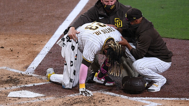 Apr 5, 2021; San Diego, California, USA; San Diego Padres shortstop Fernando Tatis Jr. (23) is looked at by a trainer after injuring himself during a swing as manager Jayce Tingler (R) assists during the third inning against the San Francisco Giants at Petco Park. Mandatory Credit: Orlando Ramirez-USA TODAY Sports