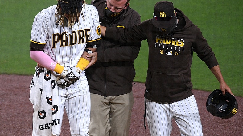 Apr 5, 2021; San Diego, California, USA; San Diego Padres shortstop Fernando Tatis Jr. (L) is helped off the field by a trainer and manager Jayce Tingler (R) after injuring himself during a swing during the third inning against the San Francisco Giants at Petco Park. Mandatory Credit: Orlando Ramirez-USA TODAY Sports