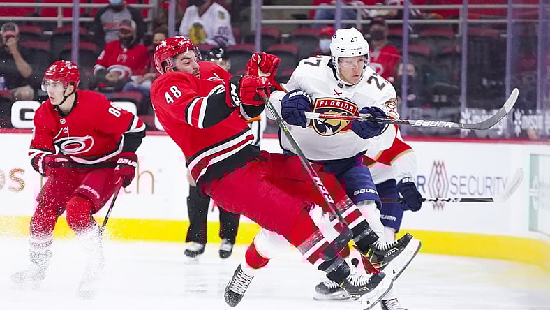 Apr 6, 2021; Raleigh, North Carolina, USA;  Florida Panthers center Eetu Luostarinen (27) checks Carolina Hurricanes left wing Jordan Martinook (48) during the first period at PNC Arena. Mandatory Credit: James Guillory-USA TODAY Sports