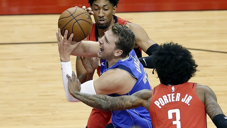 Apr 7, 2021; Houston, Texas, USA;  Dallas Mavericks guard Luka Doncic (77) is fouled as he drives to the basket between during the first half of an NBA basketball game at Toyota Center. Mandatory Credit:  Michael Wyke/POOL PHOTOS-USA TODAY Sports