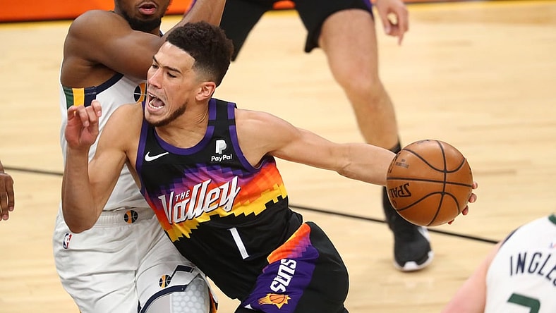 Apr 7, 2021; Phoenix, Arizona, USA; Phoenix Suns guard Devin Booker (1) reacts as he drives to the basket against Utah Jazz guard Donovan Mitchell during the first half at Phoenix Suns Arena. Mandatory Credit: Mark J. Rebilas-USA TODAY Sports