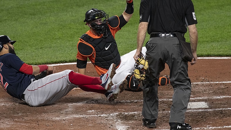 Apr 10, 2021; Baltimore, Maryland, USA; Baltimore Orioles catcher Chance Sisco (15) holds the ball up for home plate umpire Marvin Hudson (51) after tagging out Boston Red Sox third baseman Marwin Gonzalez (12) at the plate  at Oriole Park at Camden Yards. Mandatory Credit: Tommy Gilligan-USA TODAY Sports