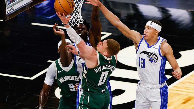 Apr 11, 2021; Orlando, Florida, USA;  Milwaukee Bucks guard Donte DiVincenzo (0) drives the the hoop over Orlando Magic guard R.J. Hampton (13) in the second quarter at Amway Center. Mandatory Credit: Nathan Ray Seebeck-USA TODAY Sports