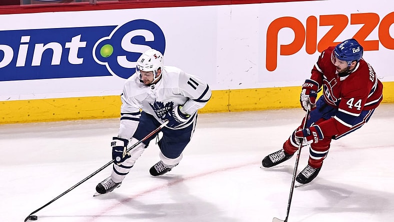 Apr 12, 2021; Montreal, Quebec, CAN; Toronto Maple Leafs left wing Zach Hyman (11) plays the puck against Montreal Canadiens defenseman Joel Edmundson (44) during the first period at Bell Centre. Mandatory Credit: Jean-Yves Ahern-USA TODAY Sports
