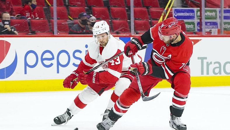 Apr 12, 2021; Raleigh, North Carolina, USA; Carolina Hurricanes defenseman Jaccob Slavin (74) and Detroit Red Wings left wing Darren Helm (43) battle over the puck during the first period at PNC Arena. Mandatory Credit: James Guillory-USA TODAY Sports