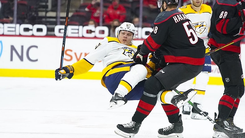 Apr 15, 2021; Raleigh, North Carolina, USA;  Carolina Hurricanes defenseman Jani Hakanpaa (58) checks Nashville Predators center Mikael Granlund (64) during the first period at PNC Arena. Mandatory Credit: James Guillory-USA TODAY Sports