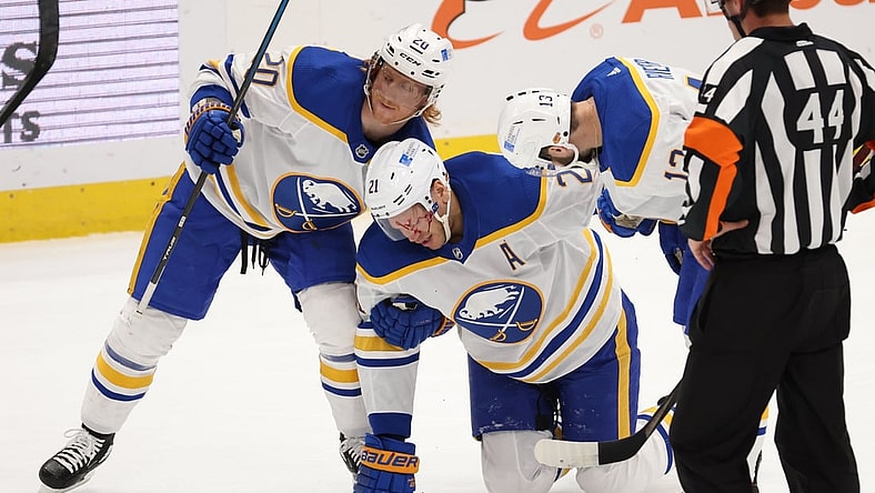 Apr 15, 2021; Washington, District of Columbia, USA; Buffalo Sabres right wing Kyle Okposo (21) is helped to his feet by Sabres center Cody Eakin (20) and Sabres left wing Tobias Rieder (13) after being struck in the face by the puck against the Washington Capitals in the first period at Capital One Arena. Mandatory Credit: Geoff Burke-USA TODAY Sports