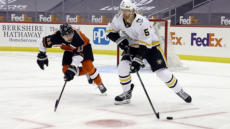 Apr 15, 2021; Pittsburgh, Pennsylvania, USA;  Pittsburgh Penguins defenseman Mike Matheson (5) moves the puck out of the defensive zone as Philadelphia Flyers right wing Travis Konecny (11) chases during the second period  at PPG Paints Arena. Mandatory Credit: Charles LeClaire-USA TODAY Sports