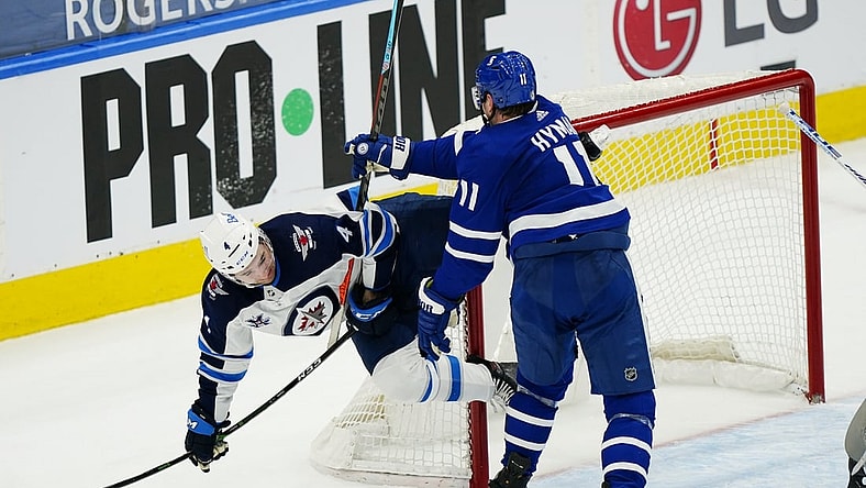 Apr 15, 2021; Toronto, Ontario, CAN; Toronto Maple Leafs forward Zach Hyman (11) knocks Winnipeg Jets defenseman Neal Pionk (4) to the ice during the third period at Scotiabank Arena. Mandatory Credit: John E. Sokolowski-USA TODAY Sports