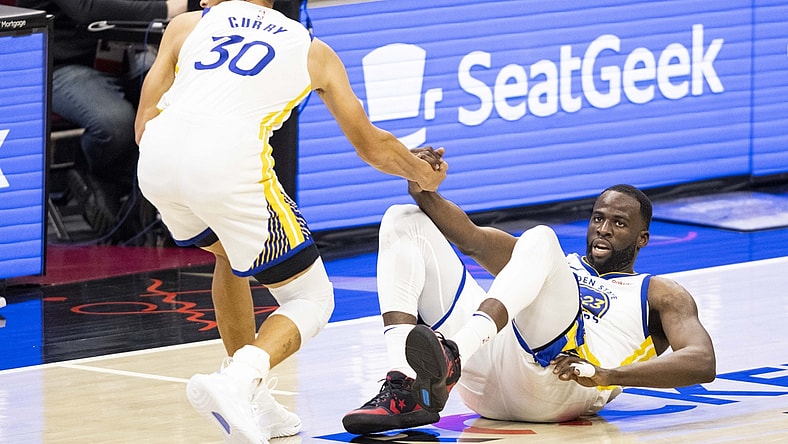 Apr 15, 2021; Cleveland, Ohio, USA; Golden State Warriors guard Stephen Curry (30) helps forward Draymond Green (23) up from the court during the third quarter against the Cleveland Cavaliers at Rocket Mortgage FieldHouse. Mandatory Credit: Scott Galvin-USA TODAY Sports