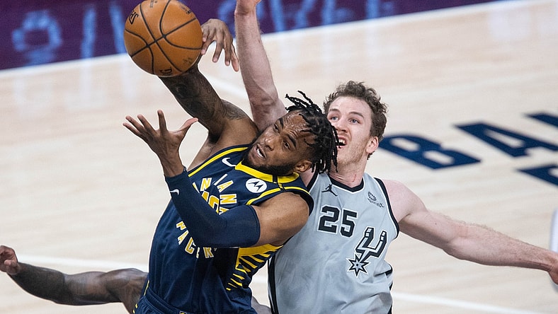 Apr 19, 2021; Indianapolis, Indiana, USA; Indiana Pacers forward Oshae Brissett (12) rebounds the ball over San Antonio Spurs center Jakob Poeltl (25)  in the second quarter at Bankers Life Fieldhouse. Mandatory Credit: Trevor Ruszkowski-USA TODAY Sports