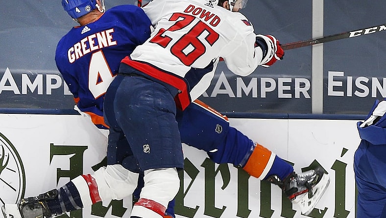 Apr 22, 2021; Uniondale, New York, USA; New York Islanders defenseman Andy Greene (4) is checked into the boards by Washington Capitals center Nic Dowd (26) during the first period at Nassau Veterans Memorial Coliseum. Mandatory Credit: Andy Marlin-USA TODAY Sports