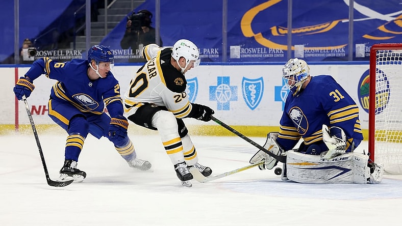 Apr 22, 2021; Buffalo, New York, USA; Buffalo Sabres defenseman Rasmus Dahlin (26) tries to defend as Boston Bruins center Curtis Lazar (20) takes a shot on Buffalo Sabres goaltender Dustin Tokarski (31) during the first period at KeyBank Center. Mandatory Credit: Timothy T. Ludwig-USA TODAY Sports