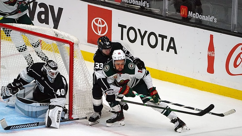 Apr 23, 2021; Los Angeles, California, USA; Minnesota Wild left wing Jordan Greenway (18) moves the puck as Los Angeles Kings defenseman Tobias Bjornfot (33) helps goaltender Calvin Petersen (40) defend the goal during the first period at Staples Center. Mandatory Credit: Gary A. Vasquez-USA TODAY Sports
