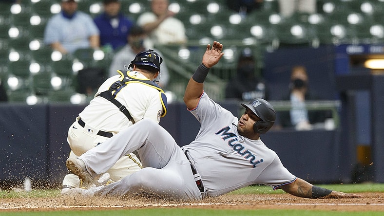 Apr 26, 2021; Milwaukee, Wisconsin, USA; Miami Marlins first baseman Jes s Aguilar (24) slides into home to score a run in front of Milwaukee Brewers catcher Manny Pi a (9) during the fourth inning at American Family Field. Mandatory Credit: Jeff Hanisch-USA TODAY Sports