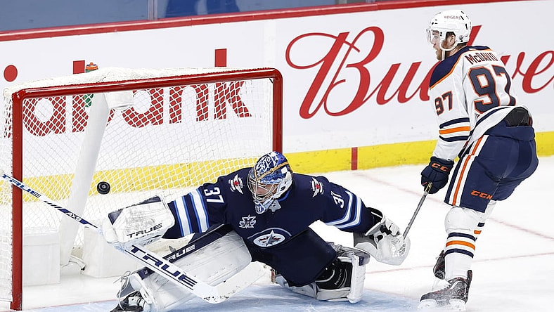 Apr 26, 2021; Winnipeg, Manitoba, CAN; Edmonton Oilers center Connor McDavid (97) scores on Winnipeg Jets goaltender Connor Hellebuyck (37) in the second period at Bell MTS Place. Mandatory Credit: James Carey Lauder-USA TODAY Sports
