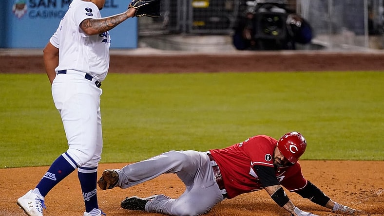 Apr 26, 2021; Los Angeles, California, USA; Cincinnati Reds right fielder Nick Castellanos (2) slide across home plate to score in the fourth inning as Los Angeles Dodgers starting pitcher Julio Urias (7) watches during the fourth inning at Dodger Stadium. Mandatory Credit: Robert Hanashiro-USA TODAY Sports