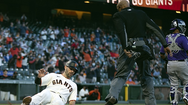 Apr 28, 2021; San Francisco, California, USA; San Francisco Giants catcher Curt Casali (left) slides safely home as he scores on a two-run RBI single hit by first baseman Brandon Belt (9) against the Colorado Rockies during the second inning as home plate umpire CB Bucknor watches at Oracle Park. Mandatory Credit: D. Ross Cameron-USA TODAY Sports