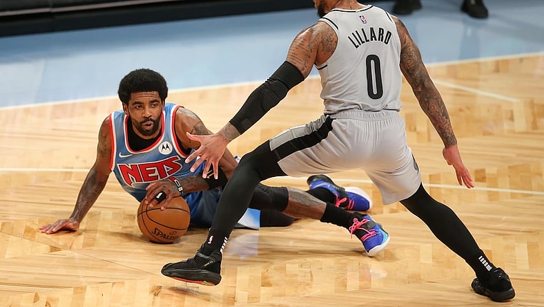 Apr 30, 2021; Brooklyn, New York, USA; Brooklyn Nets point guard Kyrie Irving (11) falls with the ball in front of Portland Trailblazers point guard Damian Lillard (0) during the first quarter at Barclays Center. Mandatory Credit: Brad Penner-USA TODAY Sports