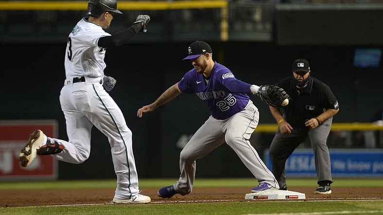Apr 30, 2021; Phoenix, Arizona, USA; Arizona Diamondbacks shortstop Nick Ahmed (13) reaches first base safely as Colorado Rockies first baseman C.J. Cron (25) misplays a throw during the second inning at Chase Field. Mandatory Credit: Joe Camporeale-USA TODAY Sports