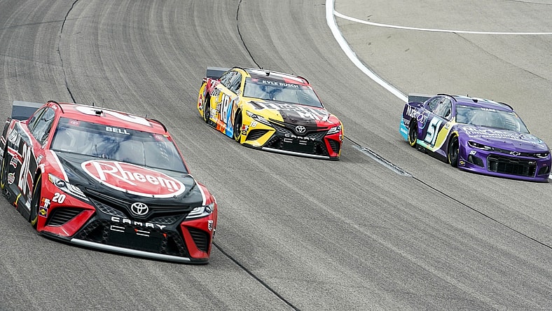 May 2, 2021; Kansas City, Kansas, USA; NASCAR Cup Series driver Kyle Busch (18) races against driver Christopher Bell (20) and driver Cody Ware (51) during the Buschy McBusch Race 400 at Kansas Speedway. Mandatory Credit: Jay Biggerstaff-USA TODAY Sports